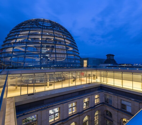 TAFB6D Illuminated glass dome on top of the Reichstag (German parliament) building in Berlin, Germany at twilight. Fernsehturm TV Tower is in the background.
